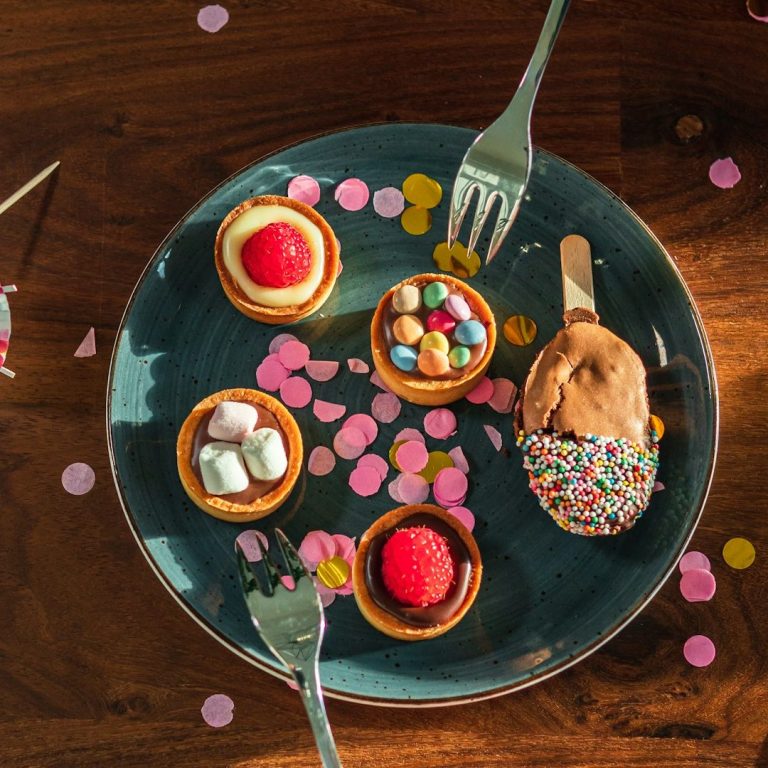 A plate full of colourful cakes surrounded by confetti.